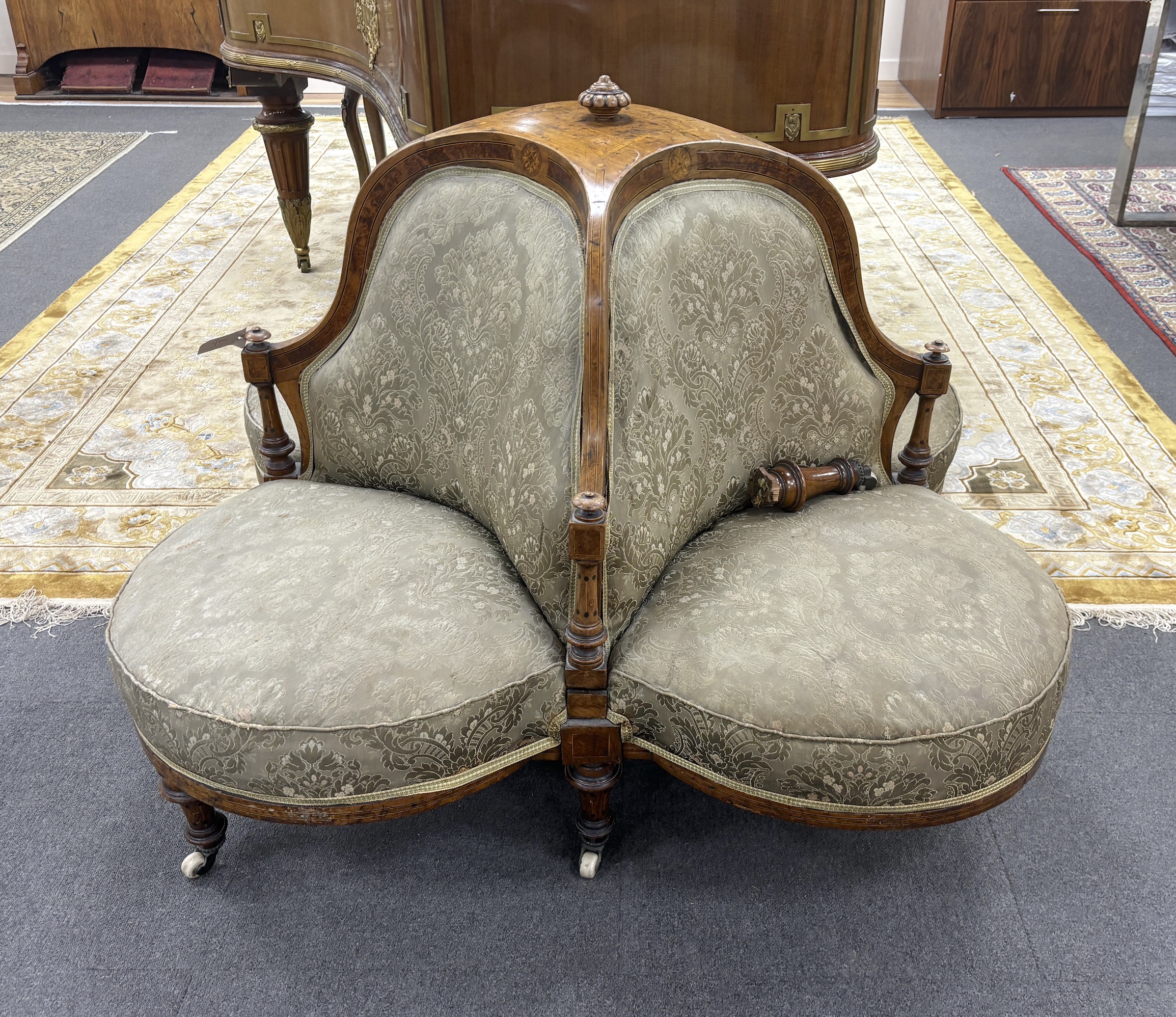 A late Victorian amboyna banded walnut conversation seat, (one leg detached), width 140cm, height 86cm
